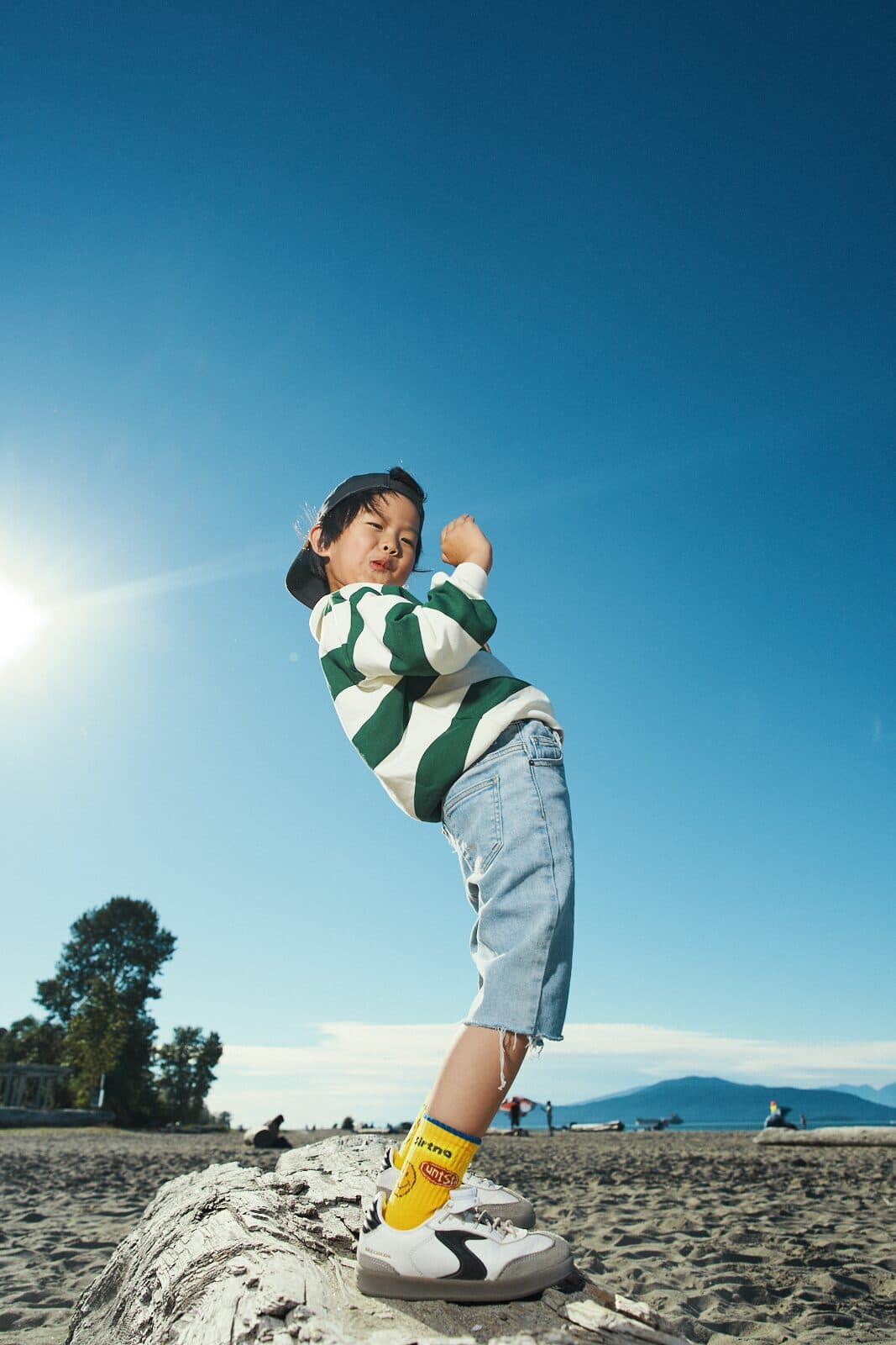 Commercial kids photography with child playing on driftwood in golden sunlight in Vancouver by Una Zhu
