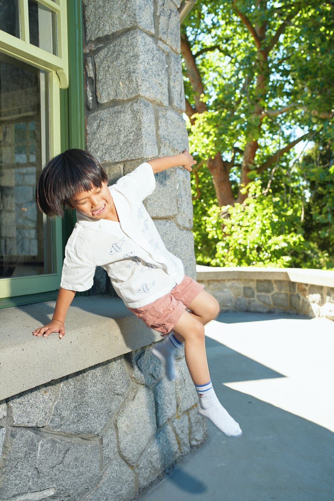 Kids commercial campaign with child jumping from a heritage stone ledge in summer apparel by Una Zhu