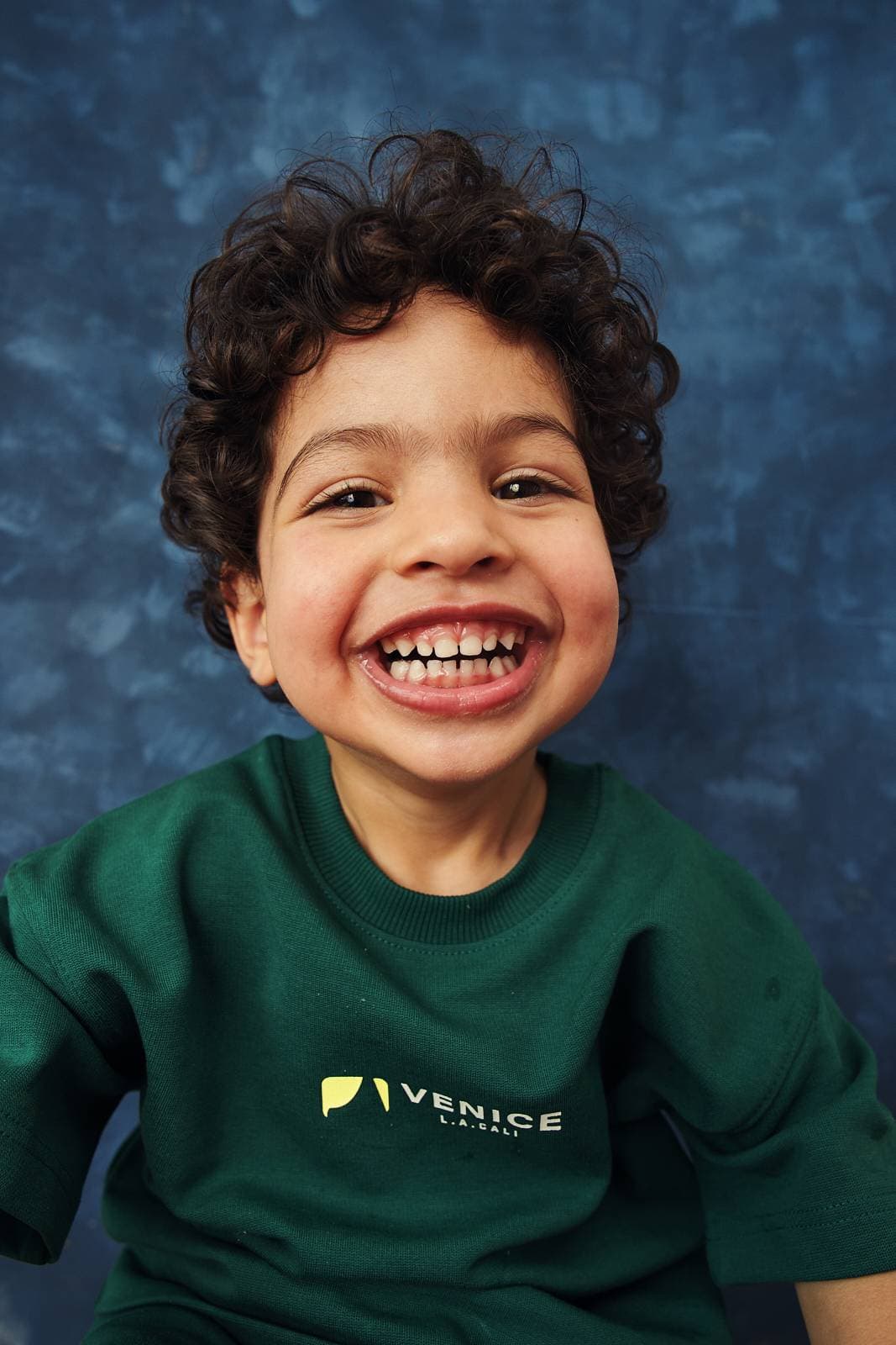 Preschool child actor headshot of a smiling boy on a classic blue mottled backdrop for agency submission in Vancouver by Una Zhu