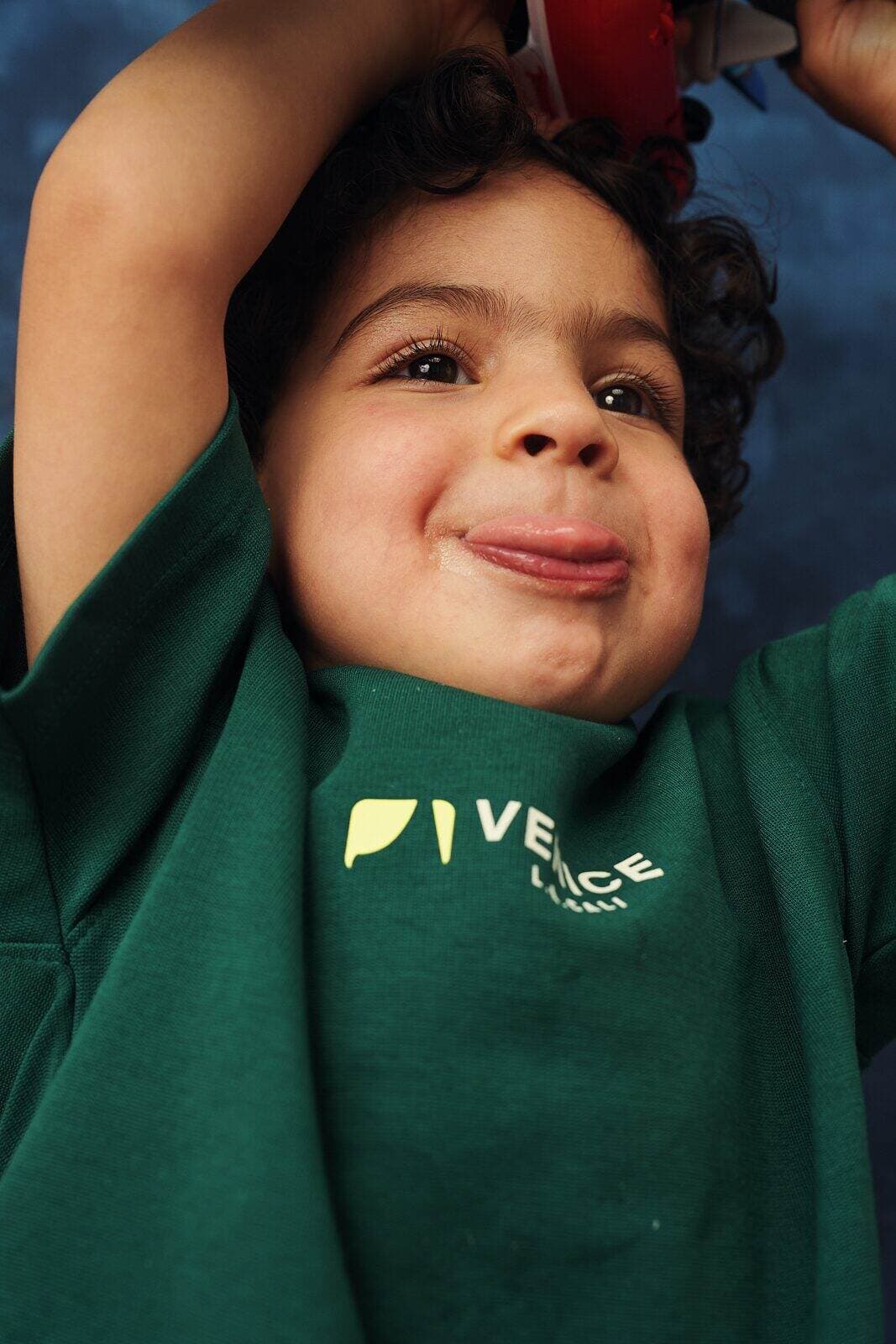Close up child actor headshot of a preschooler pulling a playful face on a blue studio backdrop in Vancouver by Una Zhu