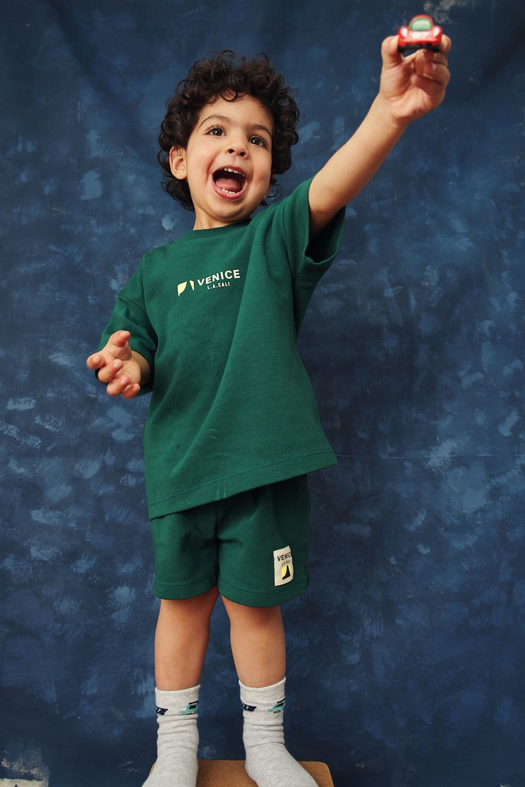 Full length child model portfolio shot of a preschooler reaching up on a blue studio backdrop in Vancouver by Una Zhu