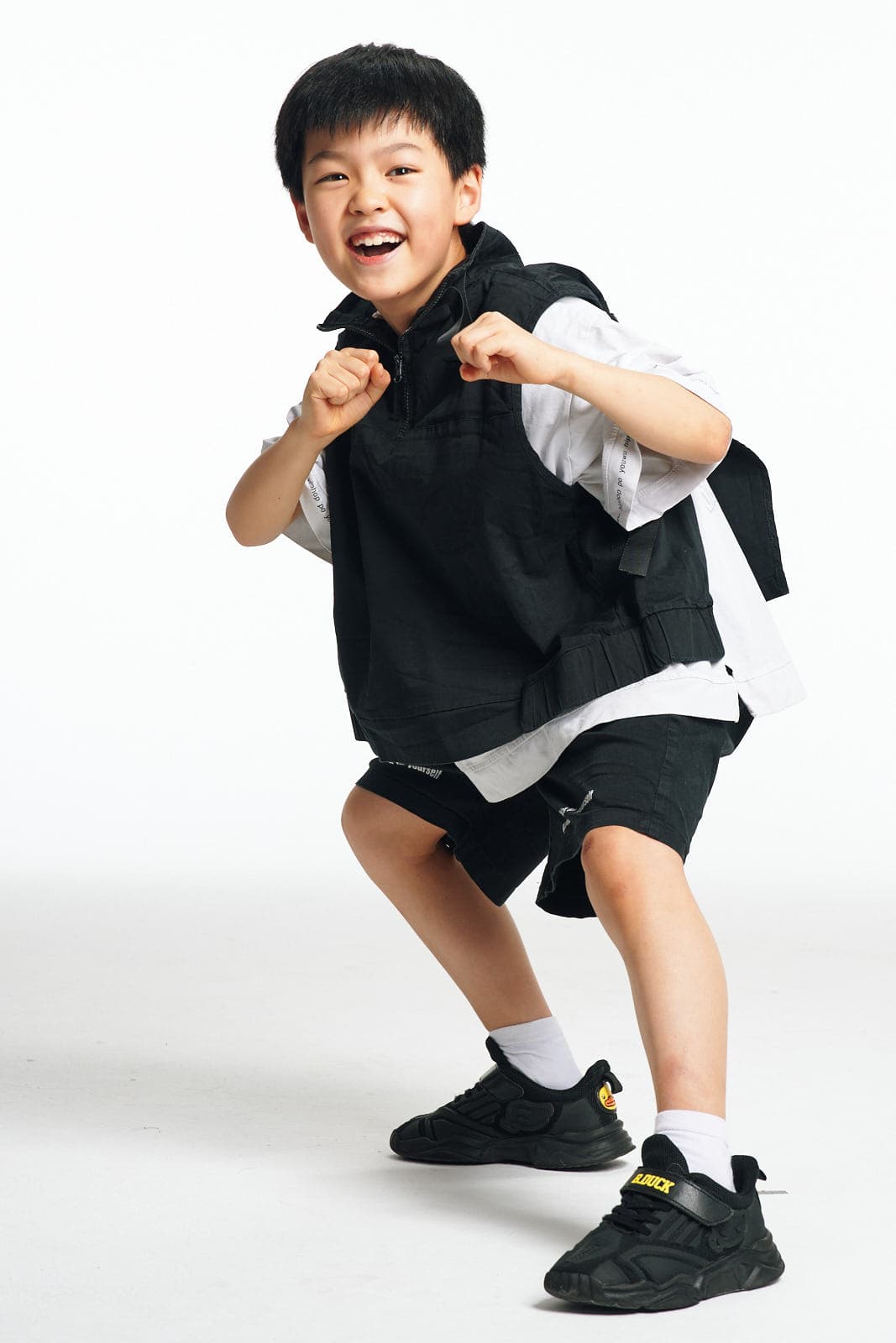 Kids model portfolio shot of boy in black streetwear with dynamic pose in Vancouver by Una Zhu