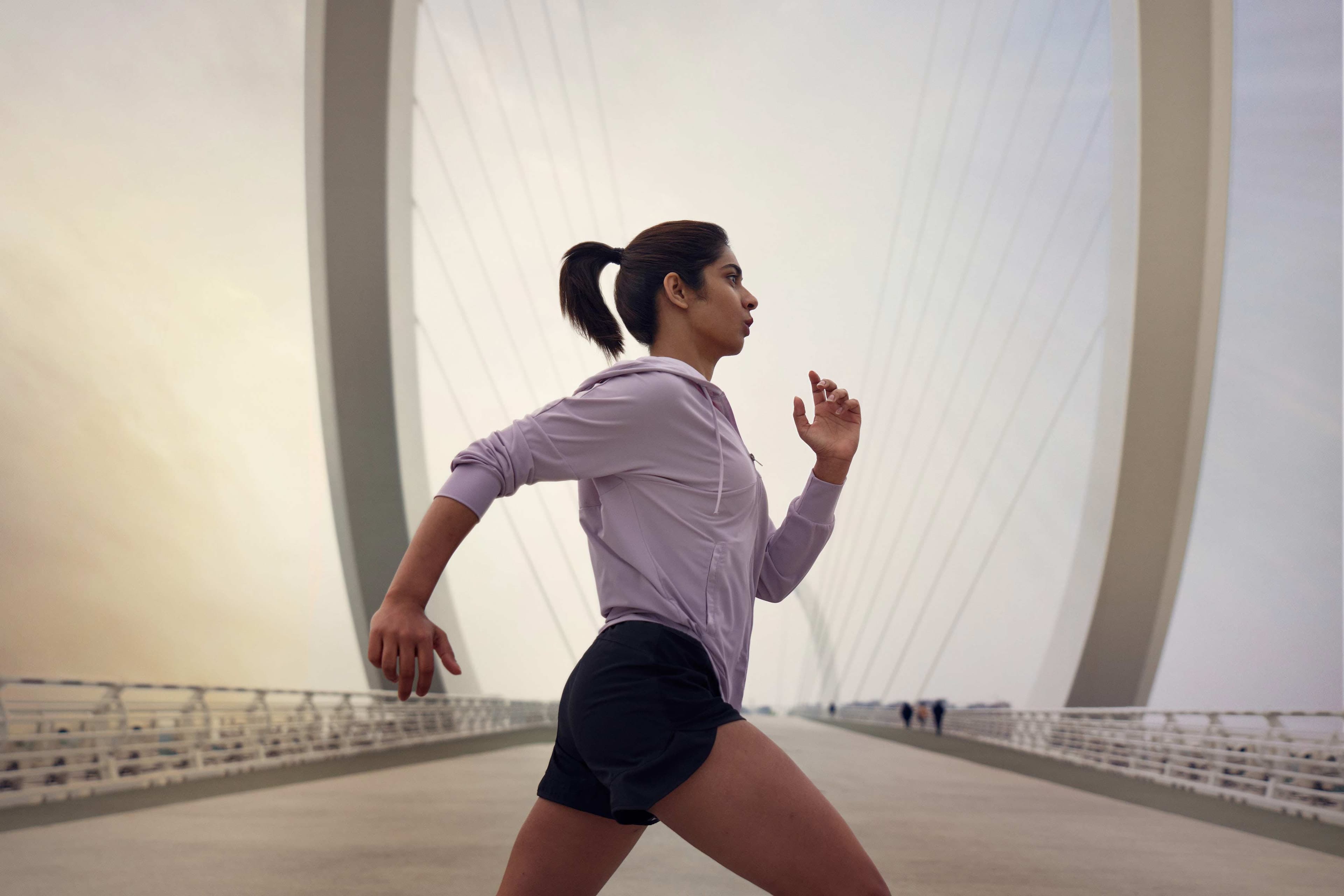 Commercial activewear video production with runner on modern bridge at sunset by Una Zhu