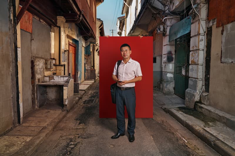 Documentary portrait of office worker standing in old Shanghai alleyway with red backdrop by Una Zhu