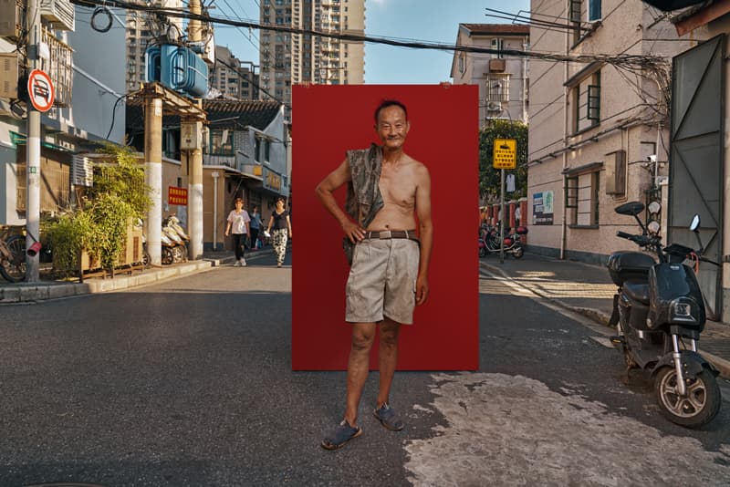 Documentary portrait of shirtless man posing confidently against red backdrop on Shanghai street by Una Zhu