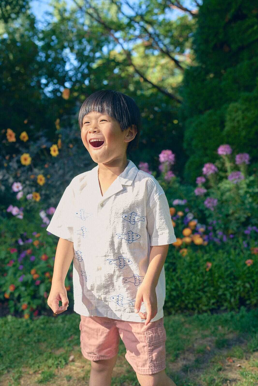 Unposed photo of a boy laughing in a summer garden during a Vancouver play session by Una Zhu