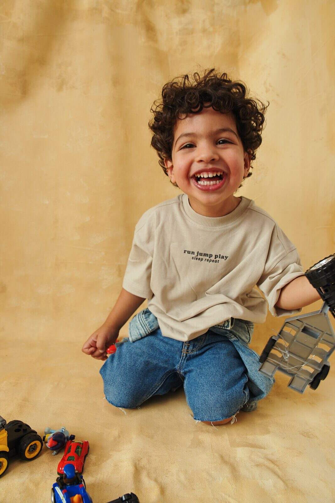 Unposed portrait of a toddler laughing in the middle of playing by Una Zhu