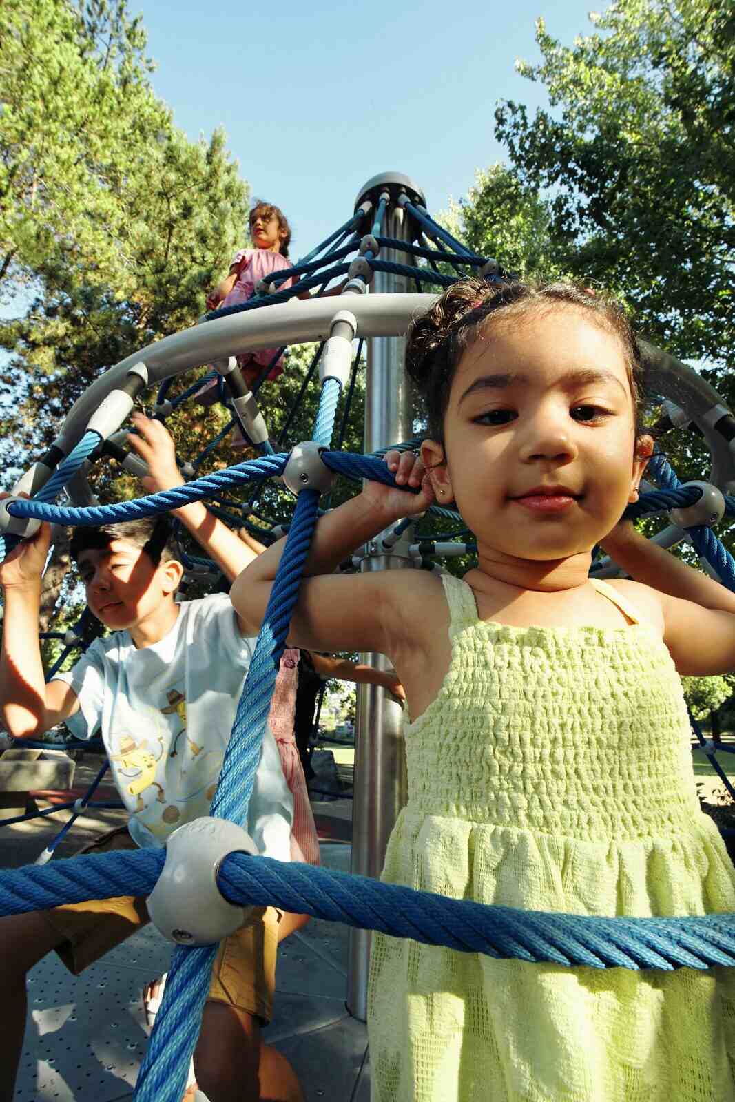 Candid photo of a girl climbing a rope structure at a Vancouver playground by Una Zhu
