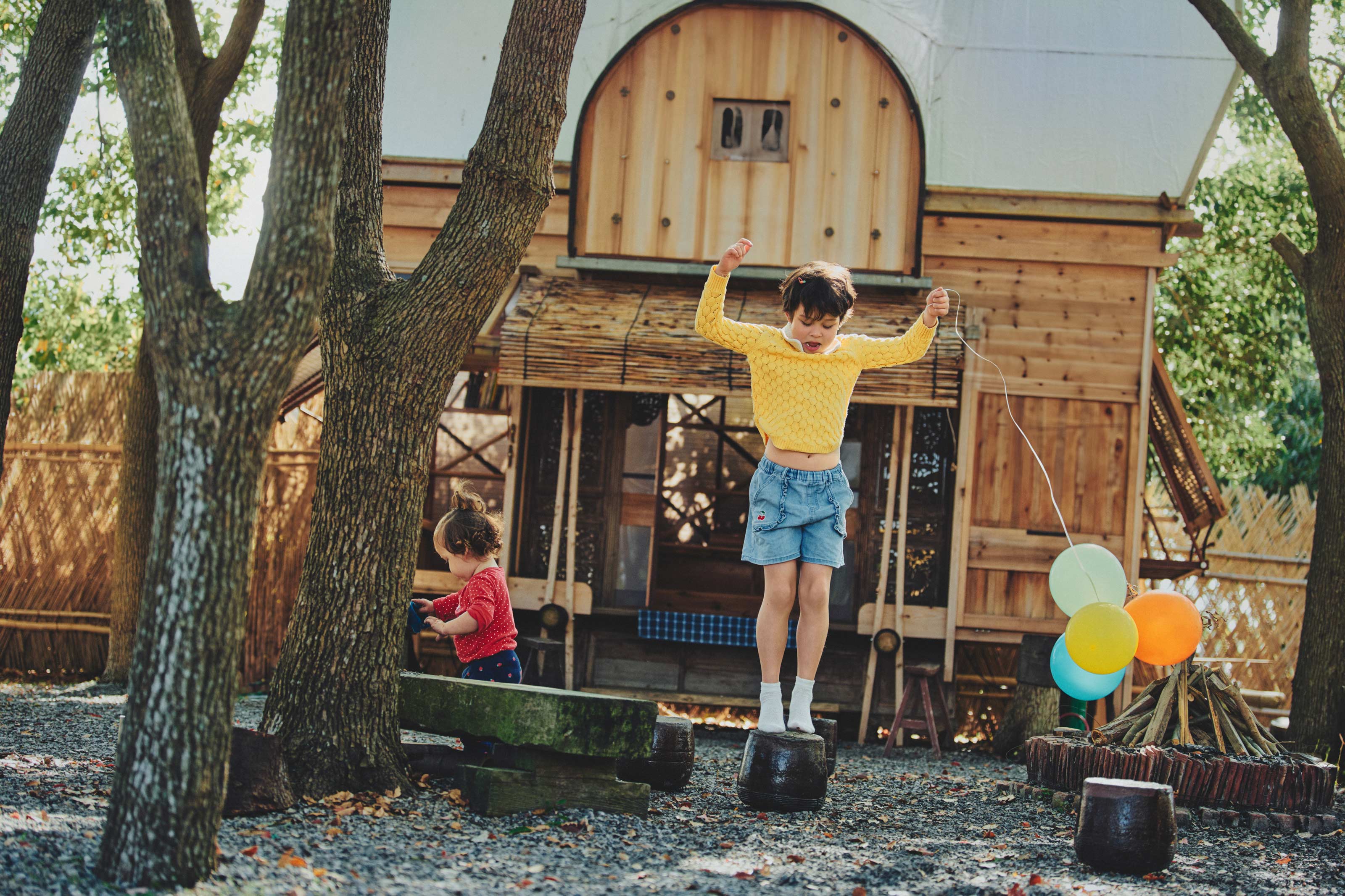 Lifestyle children campaign with kids playing at treehouse with balloons outdoors by Una Zhu