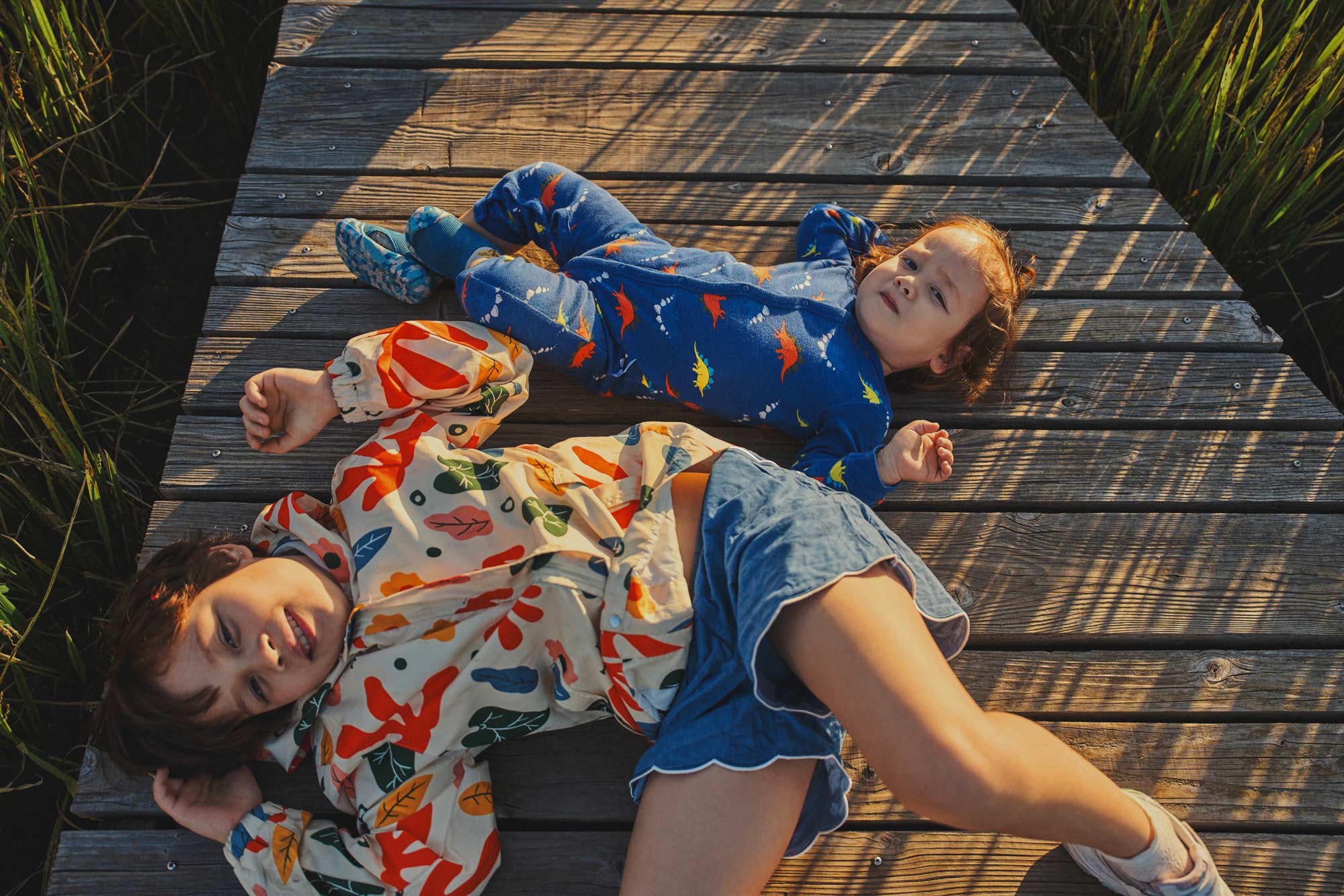 Editorial children clothing campaign with kids in printed apparel lying on wooden deck by Una Zhu