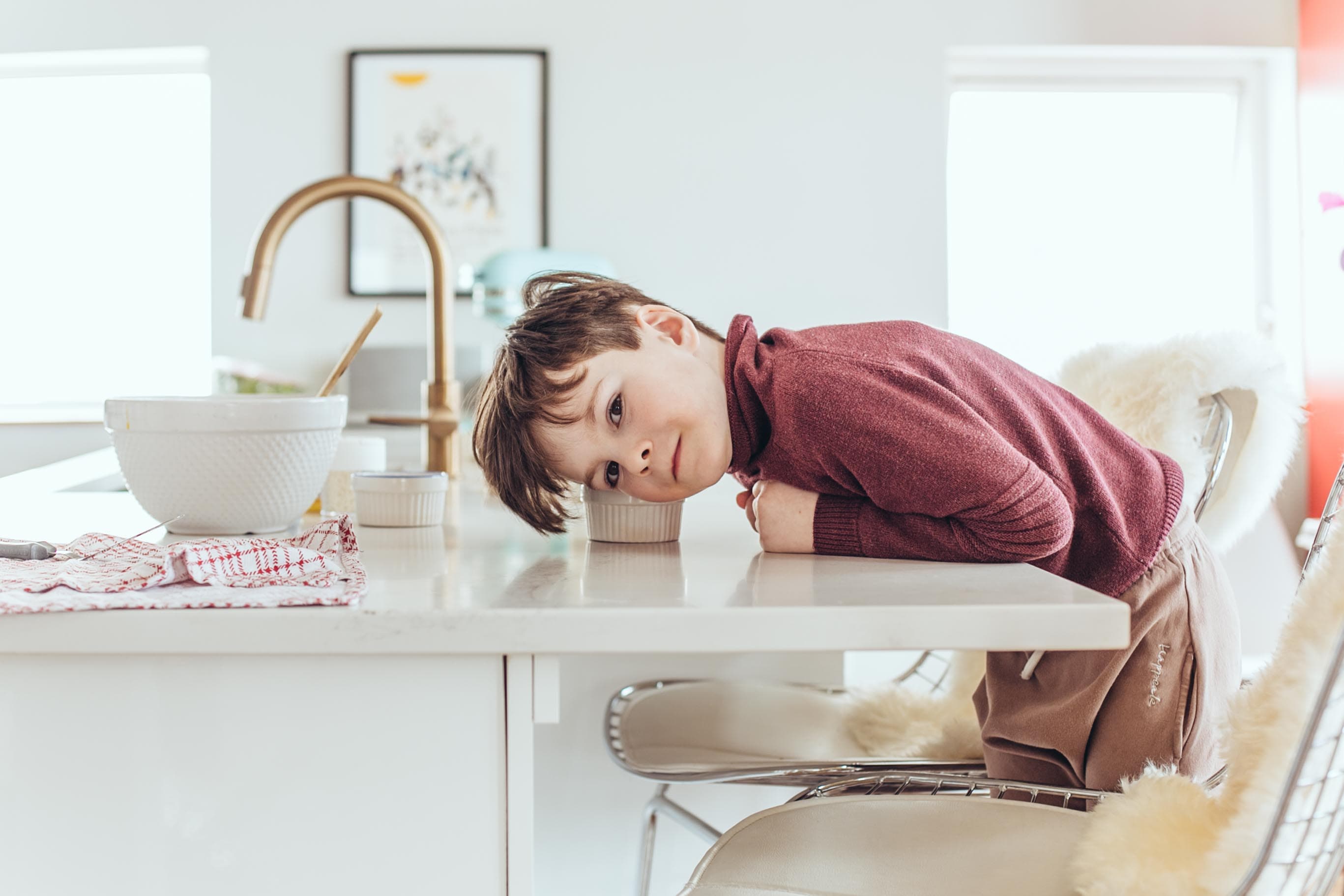 Minimalist lifestyle portrait of child resting in kitchen for kids apparel brand by Una Zhu