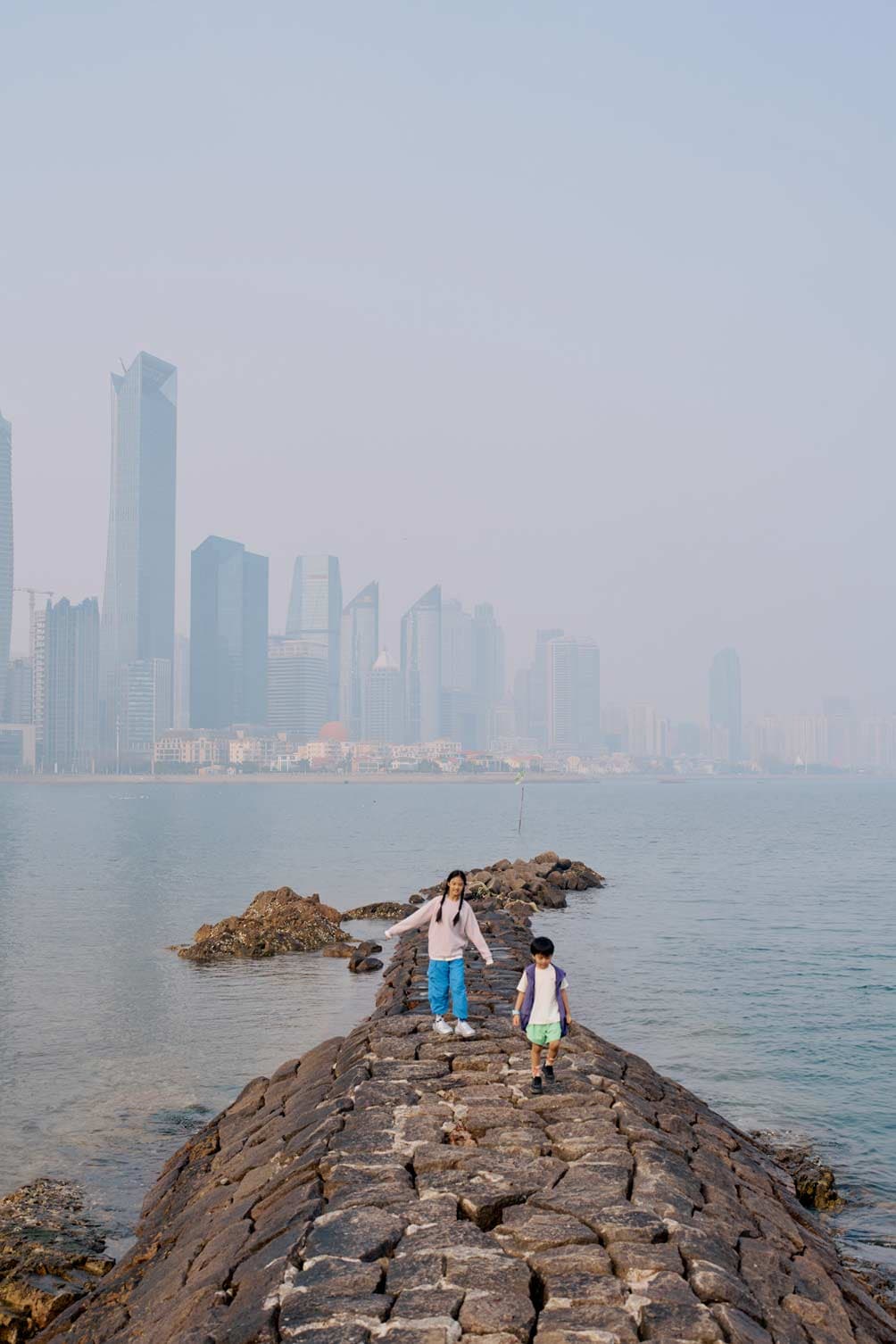 Lifestyle kids fashion campaign with children walking on jetty with city skyline by Una Zhu