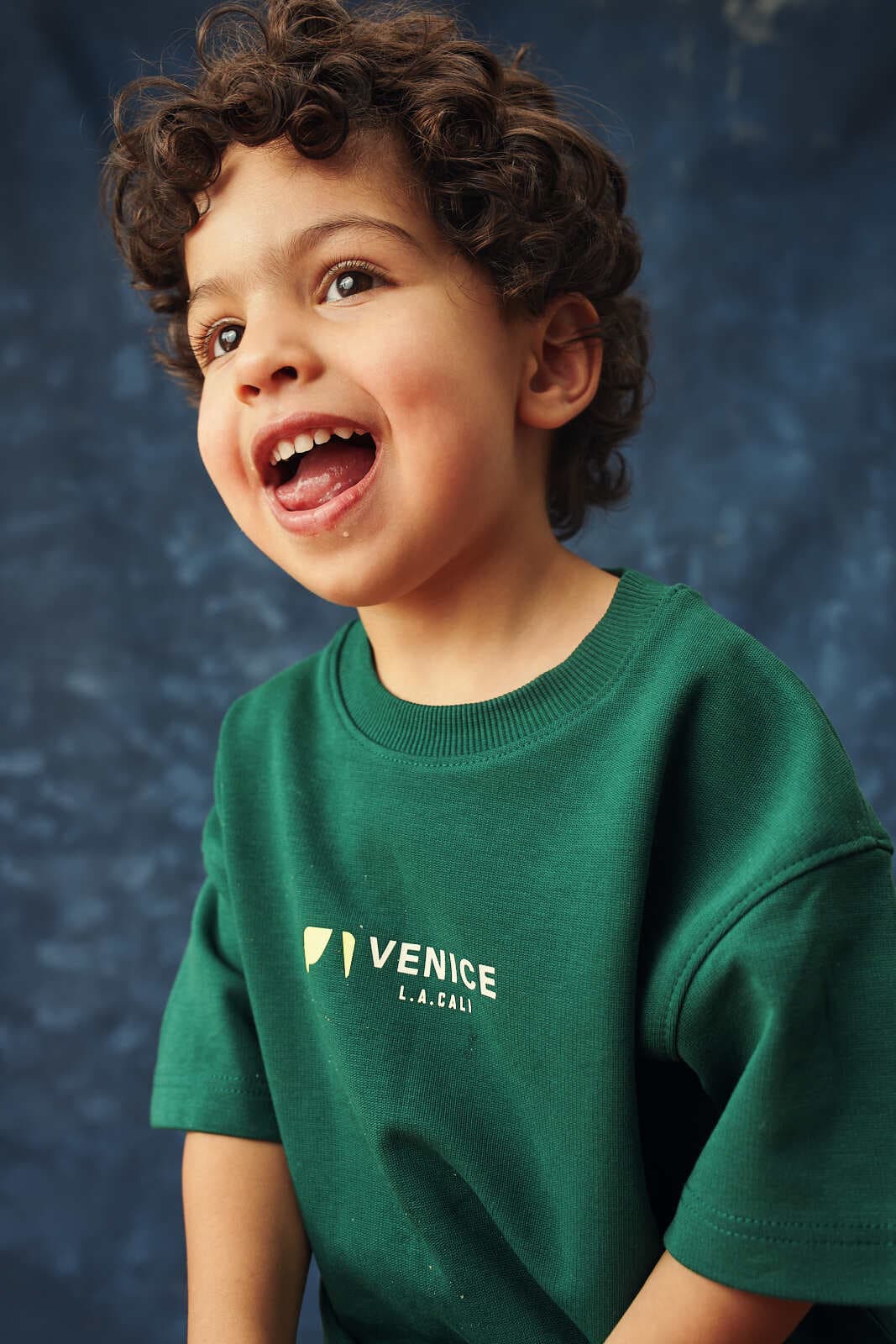Studio headshot of a young performer on a blue backdrop, shot for talent portfolio use in Vancouver by Una Zhu