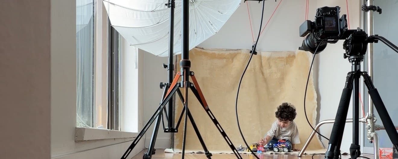Behind the scenes of a kids headshot session in Vancouver with studio lighting, backdrop and camera set up around a child at play, by Una Zhu
